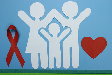 Red Ribbon and Paper silhouette of family. AIDS awareness symbol