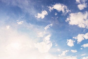 Beautiful white small soft fluffy clouds on a pale blue sky background. Sky with sun glare