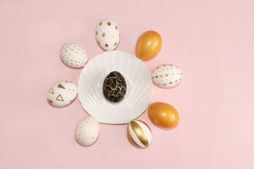 Decorated golden Easter eggs on a pink background. Minimal holiday concept. Happy Easter background. Creative painting of eggs at home.