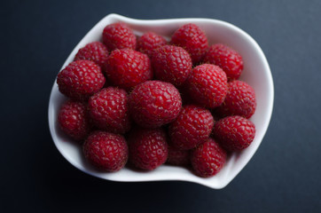 Fresh raspberries in a white pot. Flat view of red berries in a nice small white pot