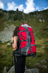 Hiker woman with backpack walking in the mountains in summer