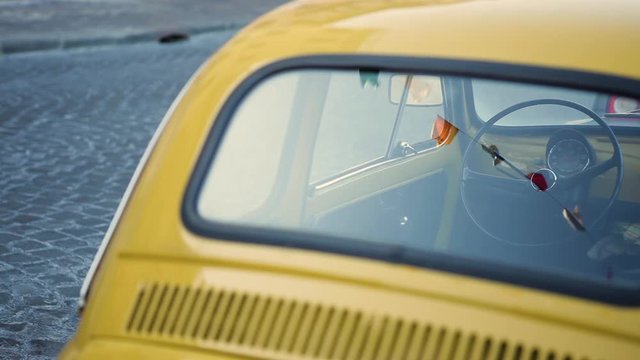 Yellow old vintage italian car with holiday flags waving on the wind reflected in its back window seamless animation. Useful as a background for travel and vacation in Europe or Italy
