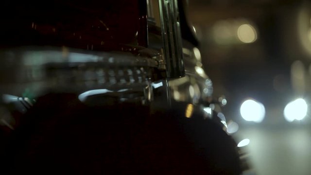 Side shot of classic luxury vintage car parked at the night street. Headlights passing by focusing on chrome shine details of beautiful dark colored oldtimer.