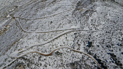 Aerial drone photo of curvy icy road in famous mountain of Penteli covered in white snow during winter time, Attica, Greece