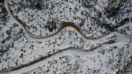 Aerial drone view of curvy road in beautiful snowed mountain in winter