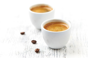 Two cups of coffee on bright wooden background. 