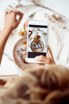 Young adult vlogger making food photo on modern smartphone