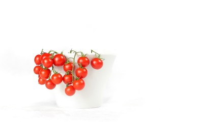 closeup of a bunch of cherry tomatoes in a cup with white background