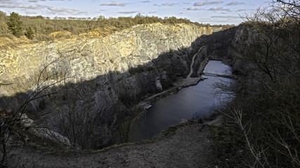 Velká America limestone quarry near the village of Mořina. Old quarry, which is partially flooded. The sun is partially shining into the mine