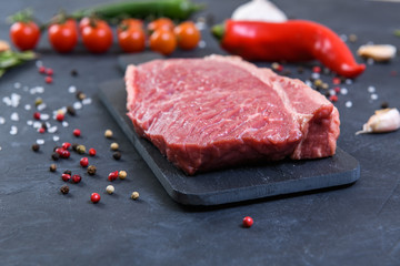 Raw fresh marbled meat and seasonings on dark background