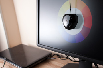 Colorimeter profiling computer monitor with color wheel image on desktop