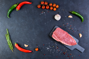 Raw fresh marbled meat and seasonings on dark background top view