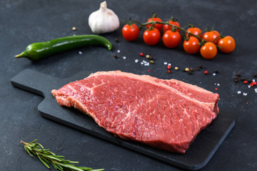 Raw fresh marbled meat and seasonings on dark background
