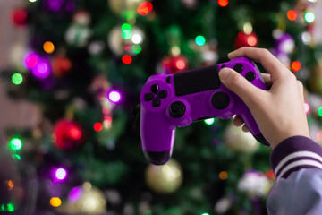 Woman's hand with a video game control with Christmas lights background and copy space. Christmas fun concept.