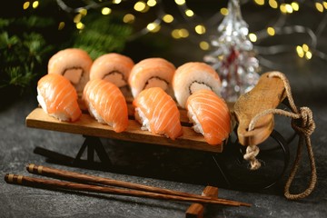 Philadelphia homemade sushi rolls and nigiri sushi with wild salmon on decorative sleigh, christmas background. 