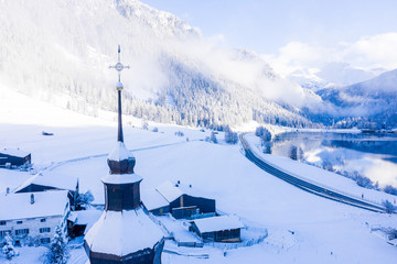 Panoramic view of scenic winter landscape in Swiss Alps with famous Church in the center of the...