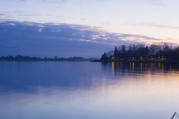 Landscape sunset lake violet sky clouds oranges sun trees on the shore reflection in the water