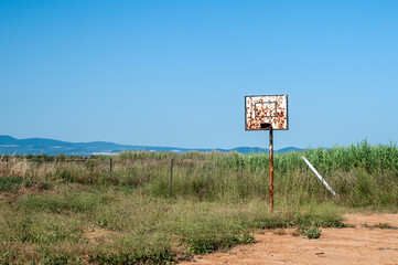 Grunge basketball board with hoop on abandoned basketball court in the beach