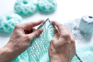 A woman knits a mint-colored sweater made of mohair yarn with the addition of a Lurex thread