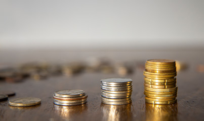 Stacks of silver and brass coins on wooden table, pile of coins in the background, white background, money growth concept