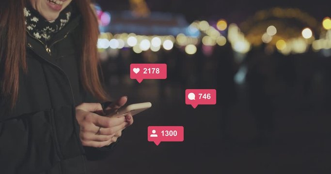Woman Hands using Mobile Phone in the City at Night. Young Woman Texting, Communicating on Cellphone Outdoors. Social Media Icons with Like Comment Follower Counter Quick Increase