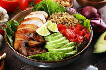 Healthy salad bowl with quinoa, tomatoes, chicken, avocado, lime and mixed greens and mushrooms