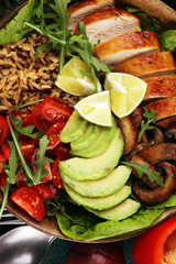 Healthy salad bowl with quinoa, tomatoes, chicken, avocado, lime and mixed greens and mushrooms