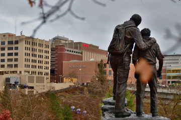 Cloudy, daytime photo of a statue of father and son overlooking downtown Spokane, Washington