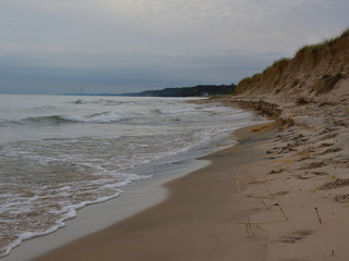 Photo of a sandy Lake Michigan beach and shoreline on a cloudy day with small waves and surf 