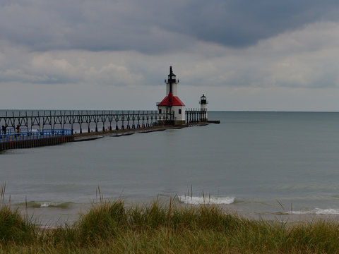 Sunrise photo of the St Joseph Michigan North Pier Lighthouse and Lake Michigan shoreline with grass in the foreground 