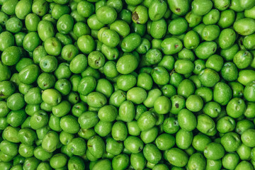 Heap of green raw olives on a indoor food market called Mercato Delle Erbe in Bologna city, Italy