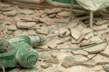 Photo of the repair process. Broken tile, dust, puncher on a blurred background.