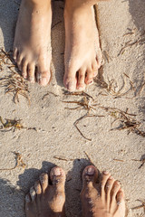 Unrecognizable people's feet on the sand at the beach face to face
