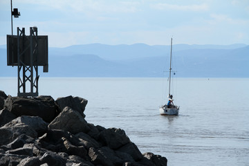 Sailing boat near jetty of rock on the saint lawrence river, Canada
