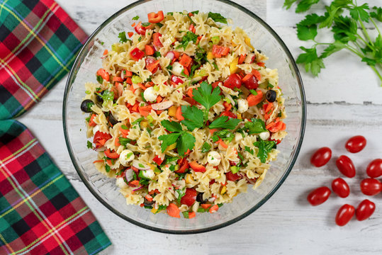 Closeup Of Pasta Salad With Fresh Vegetables And Herbs On A White Wood Background