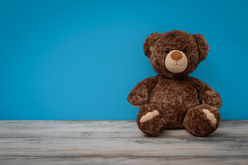 Teddybär sitzend vor einer blauen Wand