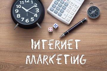 Internet marketing words written on wooden table with clock,dice,calculator pen and compass