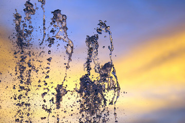 Drops of a falling water fountain against the evening sky. natural textures and backgrounds