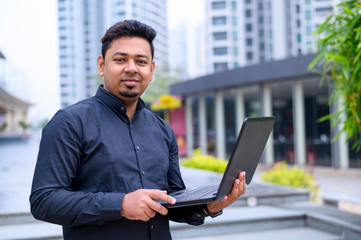 Young entrepreneur or Businessman working on laptop outside the office building.
