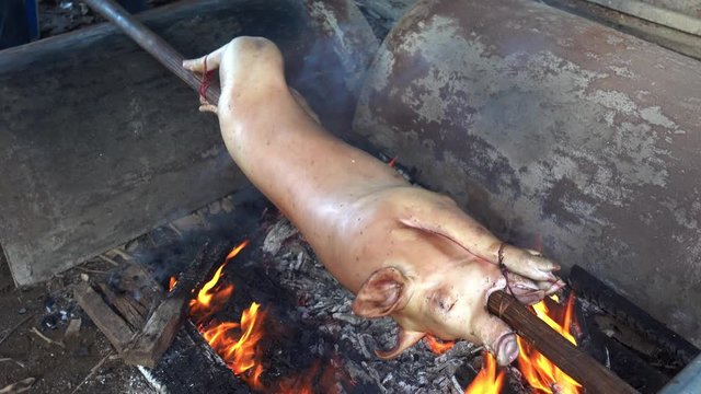 Cooking Lechon, Whole Roast Pig on Open Fire. Traditional Filippino Food