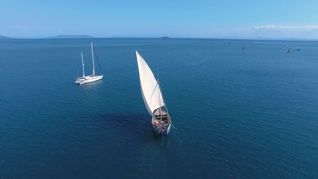 Traditional Pirogue Boat Sailing out of Bay in Madagascar. Aerial Shot of Wooden Boat with Sail Up.