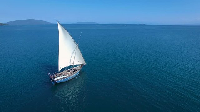 Traditional Pirogue Boat Sailing off into the ocean. Static Aerial Shot of Traditional Wooden Boat at Sail in Madagascar.