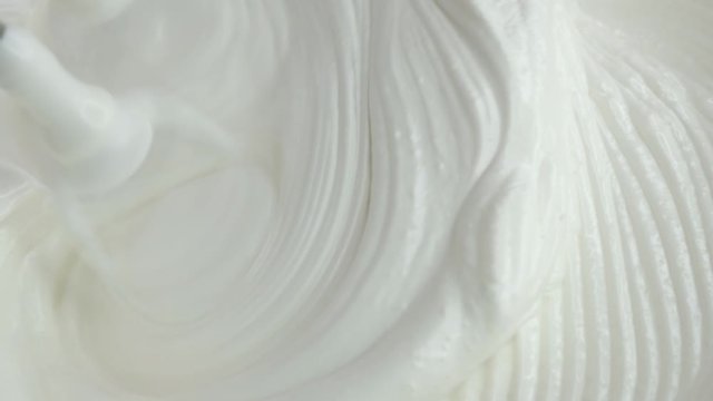 Electric mixer whips egg whites into fluffy cream. Texture thick marshmallow cream is formed while beating, close up shot of custard's texture