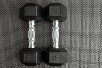 Pair of 15-pound dumbbells on a black gym floor