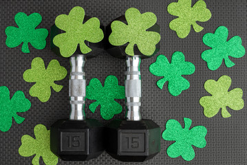 Pair of 15-pound dumbbells on a black gym floor, green shamrocks