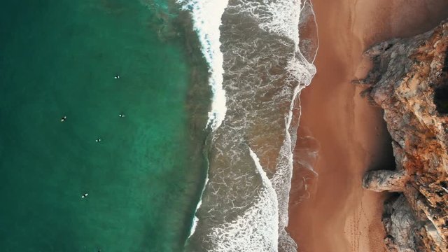 aerial shot from cliffs to the ocean with surfers waiting for a waves