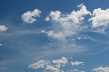 Small curly clouds run horizontally across the blue sky