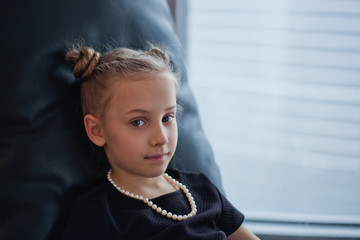 a little girl in a chair by the window of a skyscraper