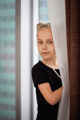 a little girl stands at the window of a skyscraper