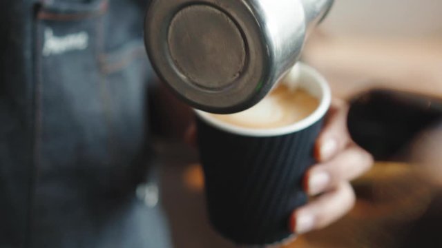 Barista Pouring Steamed Milk Unto Coffee To Make Latte Art - close up shot